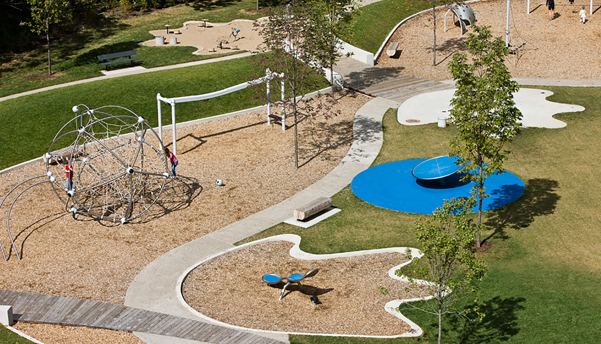 A childrens playground with swings, seesaws and a climbing frame.