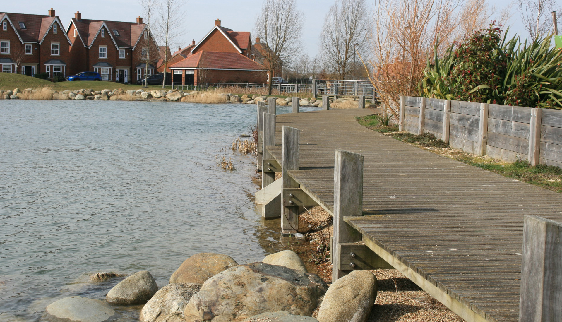 A lake with a wooden pier and houses nearby.