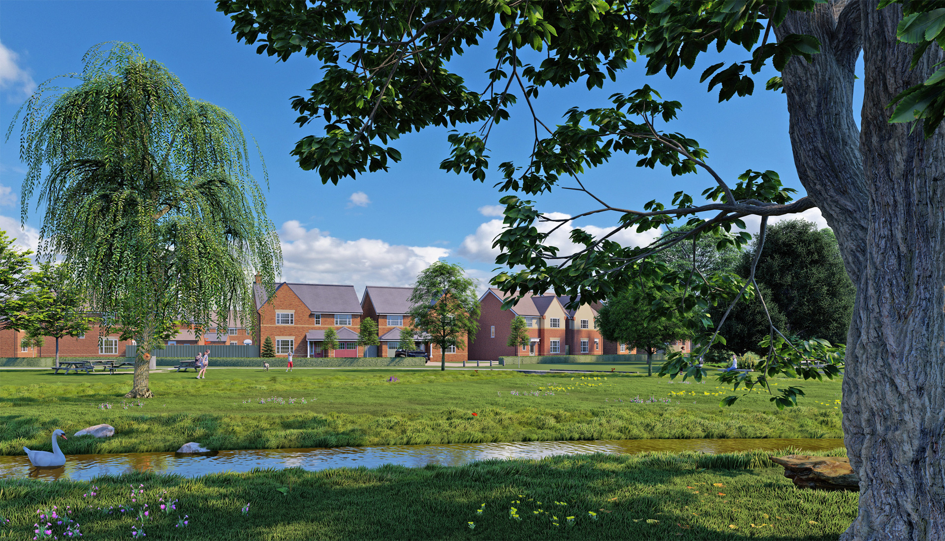 A large open space green area, with a stream and picnic benches near a row of houses.